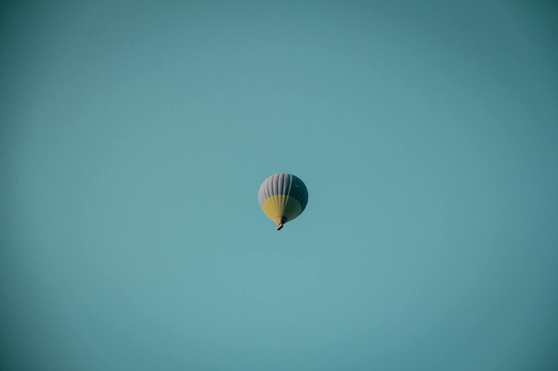 Hot air balloon rising against a clear blue sky